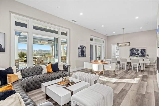 living area with recessed lighting, visible vents, light wood finished floors, and baseboards