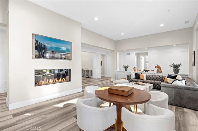 dining room featuring visible vents, baseboards, light wood-type flooring, recessed lighting, and a glass covered fireplace