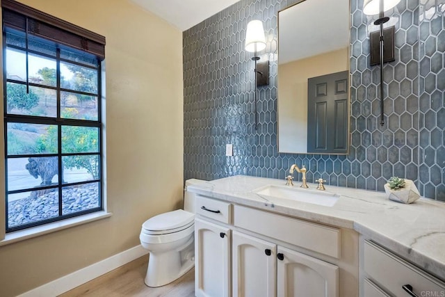 bathroom featuring toilet, vanity, decorative backsplash, and hardwood / wood-style floors