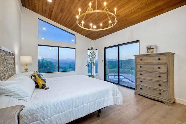 bedroom featuring access to exterior, a notable chandelier, light hardwood / wood-style floors, a mountain view, and wooden ceiling