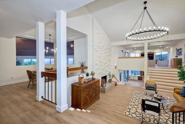 living room with light wood-type flooring, an inviting chandelier, and a fireplace