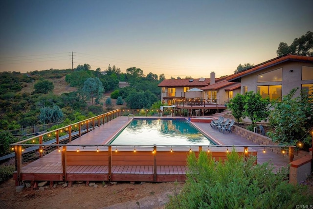 pool at dusk featuring a deck