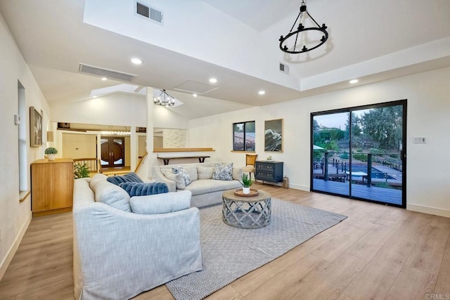 living room featuring lofted ceiling, a notable chandelier, and light wood-type flooring