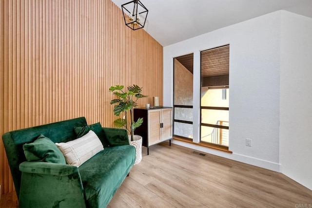 living area featuring vaulted ceiling, an inviting chandelier, and light hardwood / wood-style floors