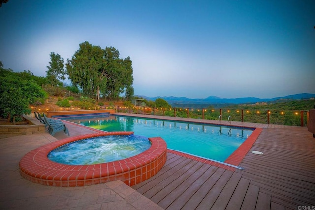 view of pool with an in ground hot tub and a deck with mountain view