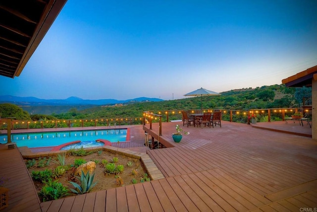 pool at dusk with a deck with mountain view