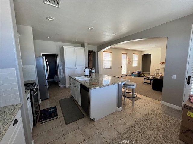 kitchen featuring appliances with stainless steel finishes, sink, a center island with sink, white cabinetry, and a breakfast bar area