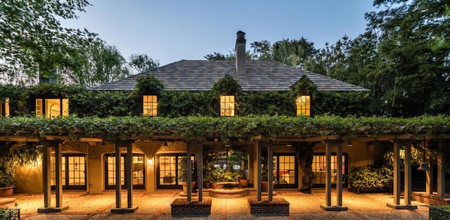 back house at dusk featuring a patio area