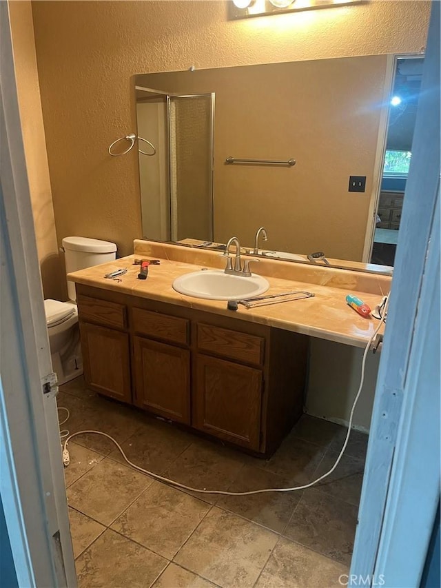 bathroom with vanity, tile patterned flooring, toilet, and a shower