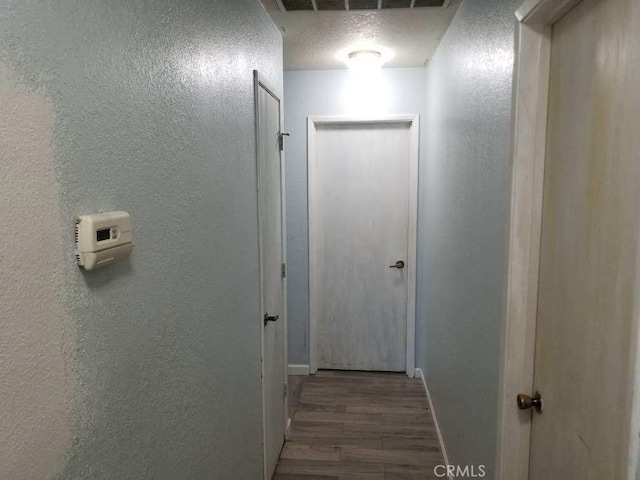 hallway with hardwood / wood-style floors and a textured ceiling