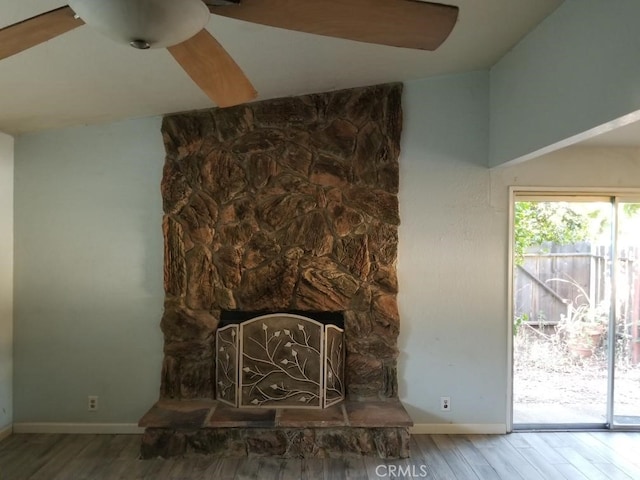 unfurnished living room featuring plenty of natural light, a fireplace, vaulted ceiling, and wood-type flooring