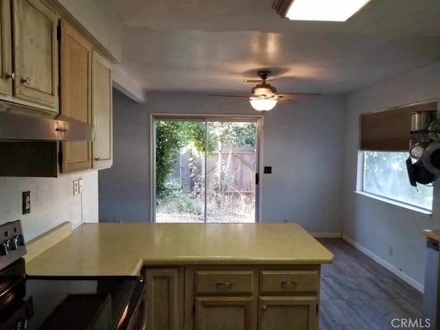 kitchen featuring plenty of natural light, kitchen peninsula, ceiling fan, and stainless steel range with electric stovetop