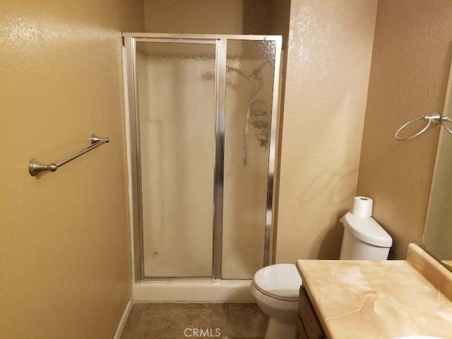 bathroom featuring vanity, an enclosed shower, tile patterned floors, and toilet