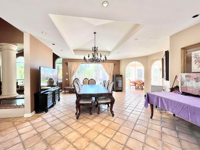 dining area featuring an inviting chandelier, decorative columns, a raised ceiling, and light tile patterned flooring