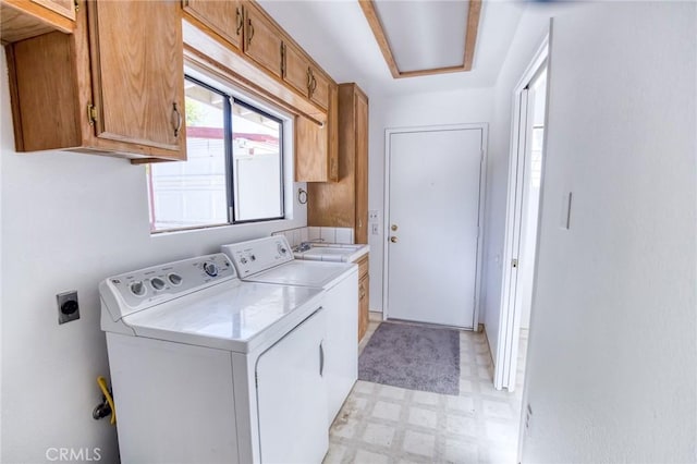 laundry area featuring cabinets, separate washer and dryer, and sink