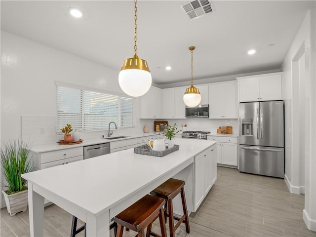 kitchen featuring white cabinets, decorative light fixtures, and stainless steel appliances