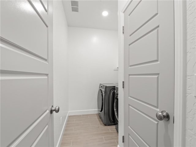 laundry area with washer and clothes dryer and light hardwood / wood-style flooring