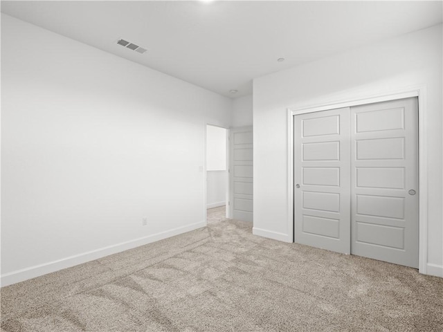 unfurnished bedroom featuring light colored carpet and a closet