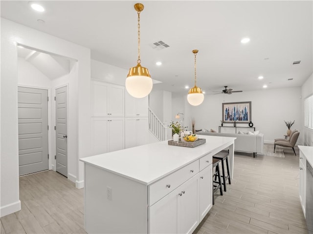 kitchen featuring white cabinets, a kitchen island, hanging light fixtures, and ceiling fan