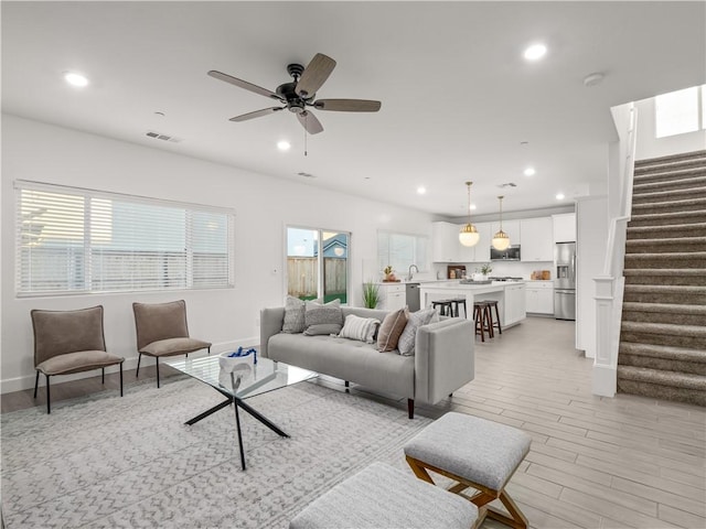 living room with sink, light wood-type flooring, a wealth of natural light, and ceiling fan