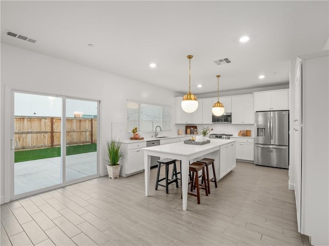 kitchen featuring white cabinets, appliances with stainless steel finishes, a center island, and sink