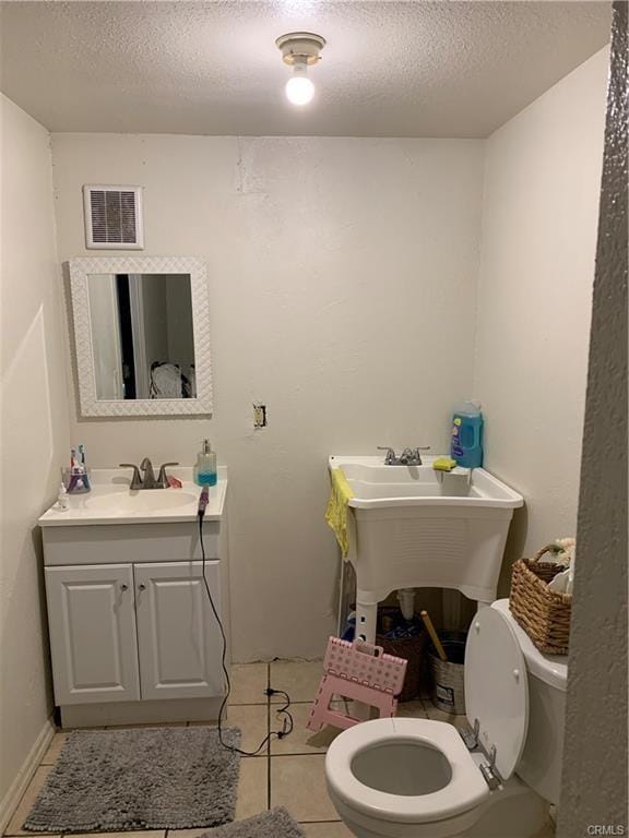 bathroom with tile patterned floors, vanity, toilet, and a textured ceiling