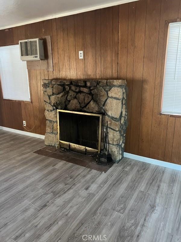 interior details with a wall mounted air conditioner, hardwood / wood-style floors, a stone fireplace, and wood walls