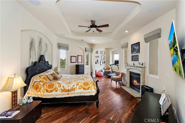 bedroom with ceiling fan, hardwood / wood-style flooring, and a tray ceiling