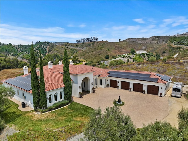 view of front of property featuring a garage, a mountain view, and solar panels