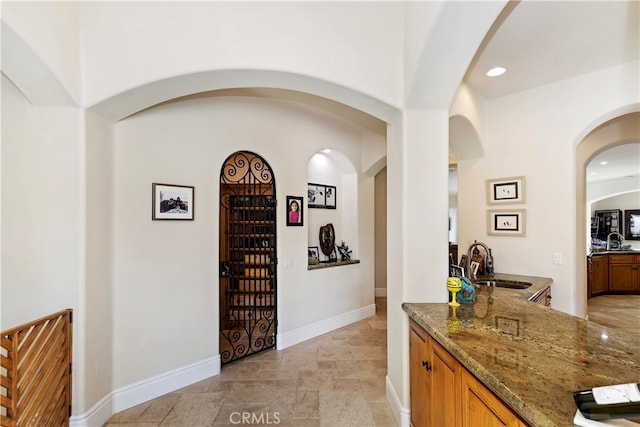 interior space featuring light tile patterned flooring, stone countertops, and sink