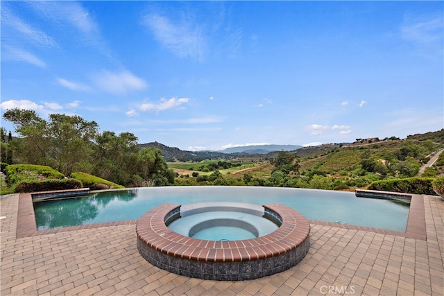 view of pool featuring an in ground hot tub and a mountain view