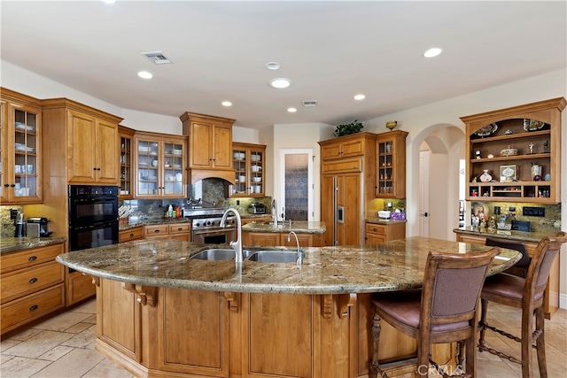 kitchen with stone counters, high quality appliances, light tile patterned floors, and backsplash