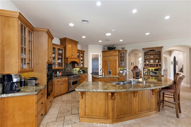 kitchen with dark stone countertops, sink, premium appliances, and light tile patterned floors