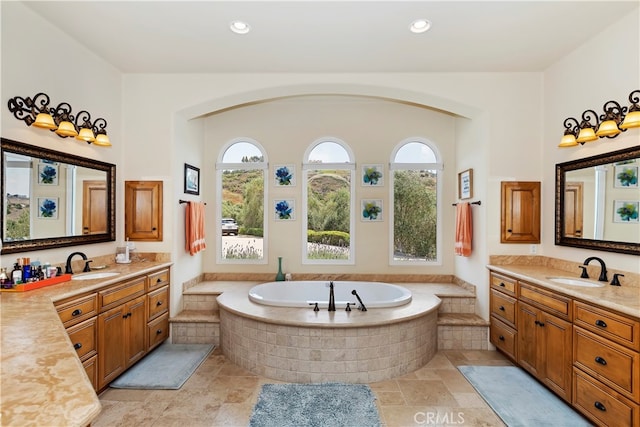 bathroom with a relaxing tiled tub, dual vanity, and tile patterned floors