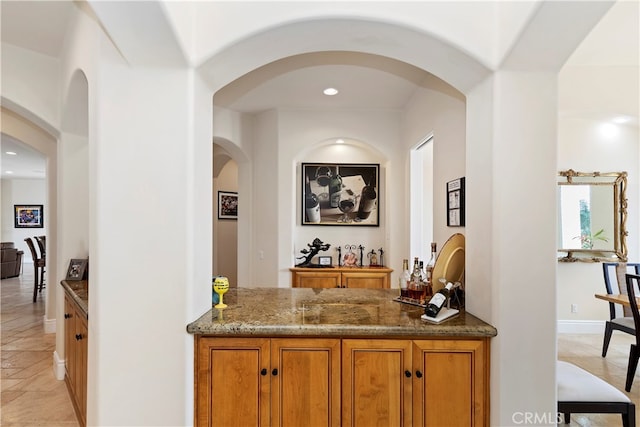 bar with light tile patterned floors and stone countertops