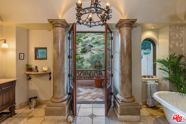 entrance foyer with decorative columns, light tile patterned floors, and a chandelier