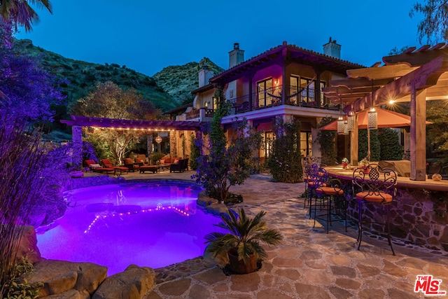 view of swimming pool with a bar, a mountain view, an outdoor living space, and a patio