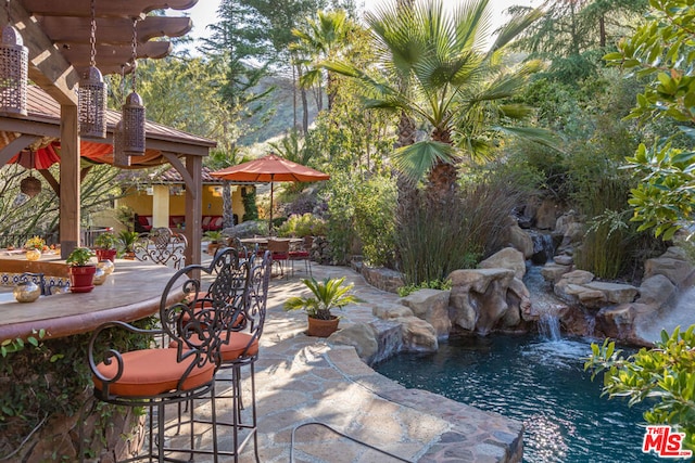 view of patio / terrace with pool water feature and a small pond