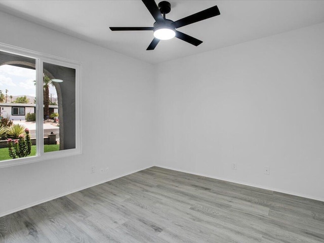 unfurnished room with a wealth of natural light, ceiling fan, and light wood-type flooring