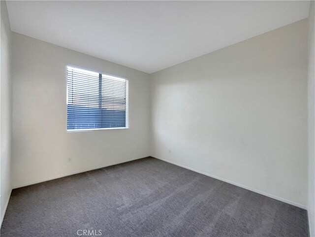 spare room with dark colored carpet