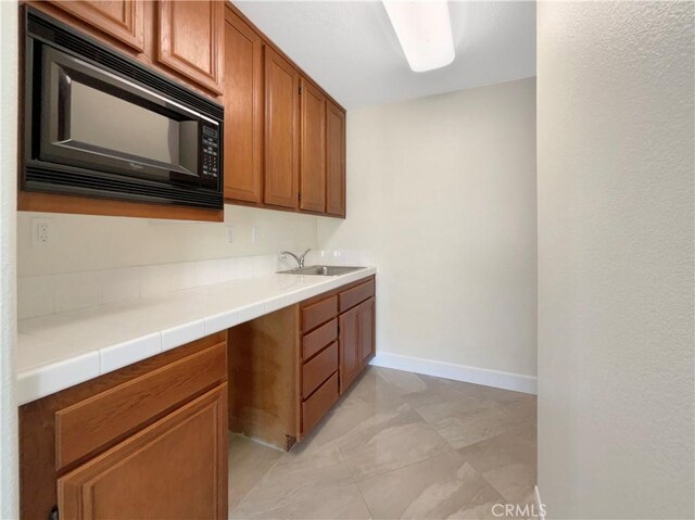 kitchen featuring sink, black microwave, and tile countertops