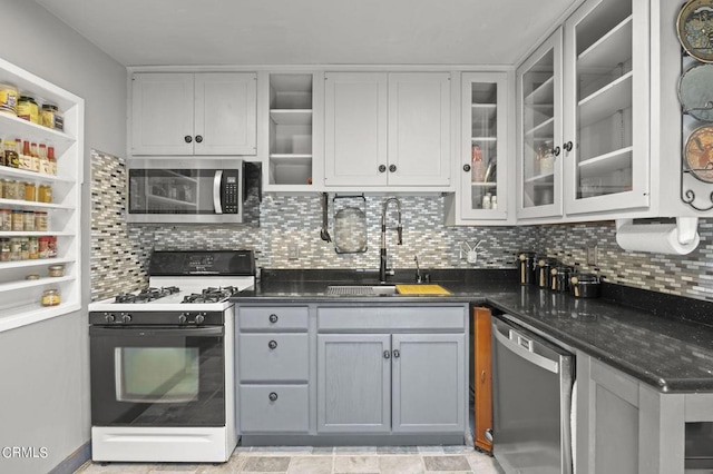 kitchen featuring a sink, glass insert cabinets, appliances with stainless steel finishes, white cabinetry, and backsplash