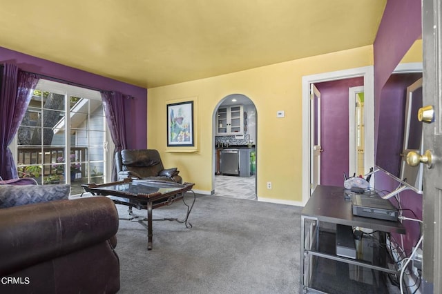 carpeted living area featuring arched walkways and baseboards