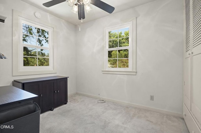 interior space with light colored carpet, baseboards, and ceiling fan