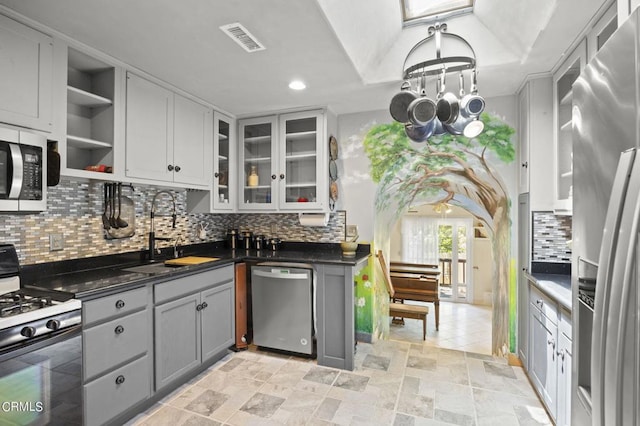 kitchen featuring visible vents, gray cabinetry, a sink, dark countertops, and appliances with stainless steel finishes