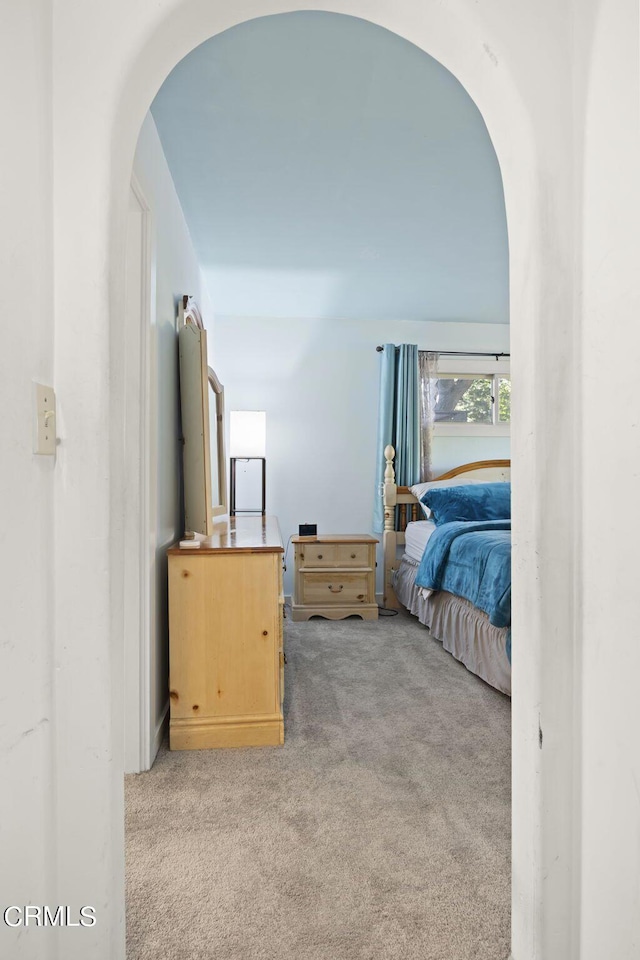 carpeted bedroom featuring arched walkways