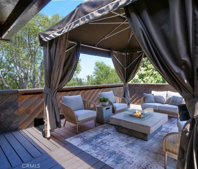 wooden terrace featuring an outdoor living space with a fire pit