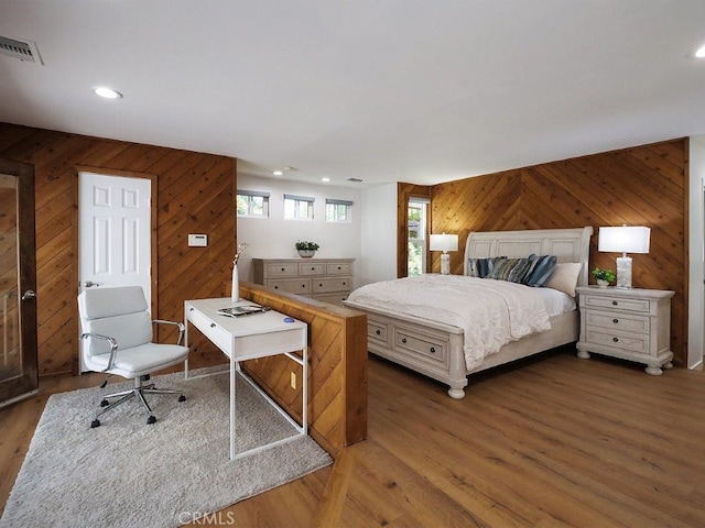 bedroom with dark hardwood / wood-style flooring and wooden walls