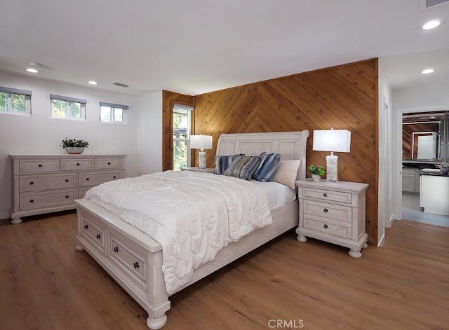 bedroom featuring dark hardwood / wood-style floors, wood walls, and multiple windows