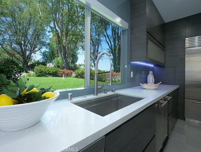 kitchen with light tile patterned floors, dishwashing machine, stainless steel fridge, and sink